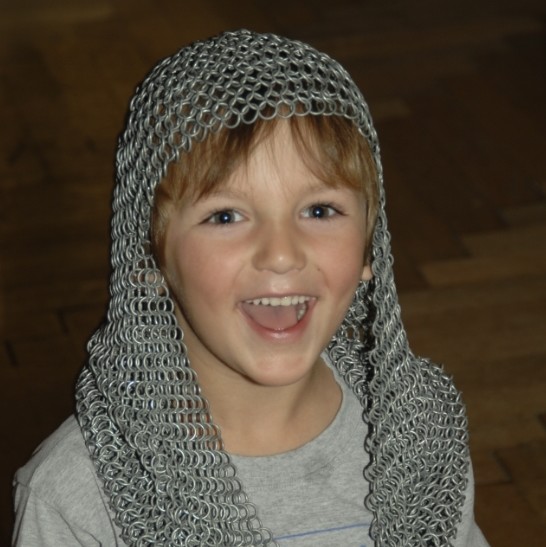Kind mit Kettenhelm als kurioser Kopfbedeckung