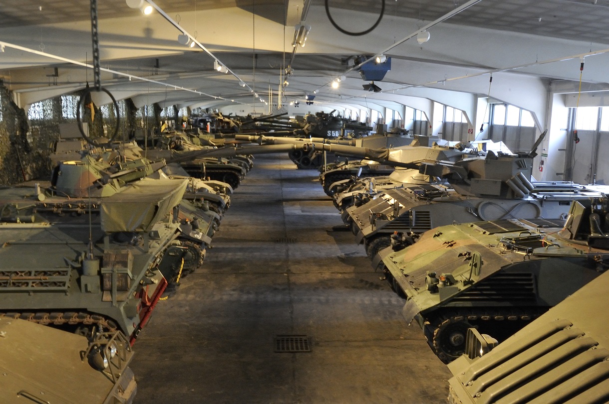 Verschiedene Panzer links und rechts in einer Halle.