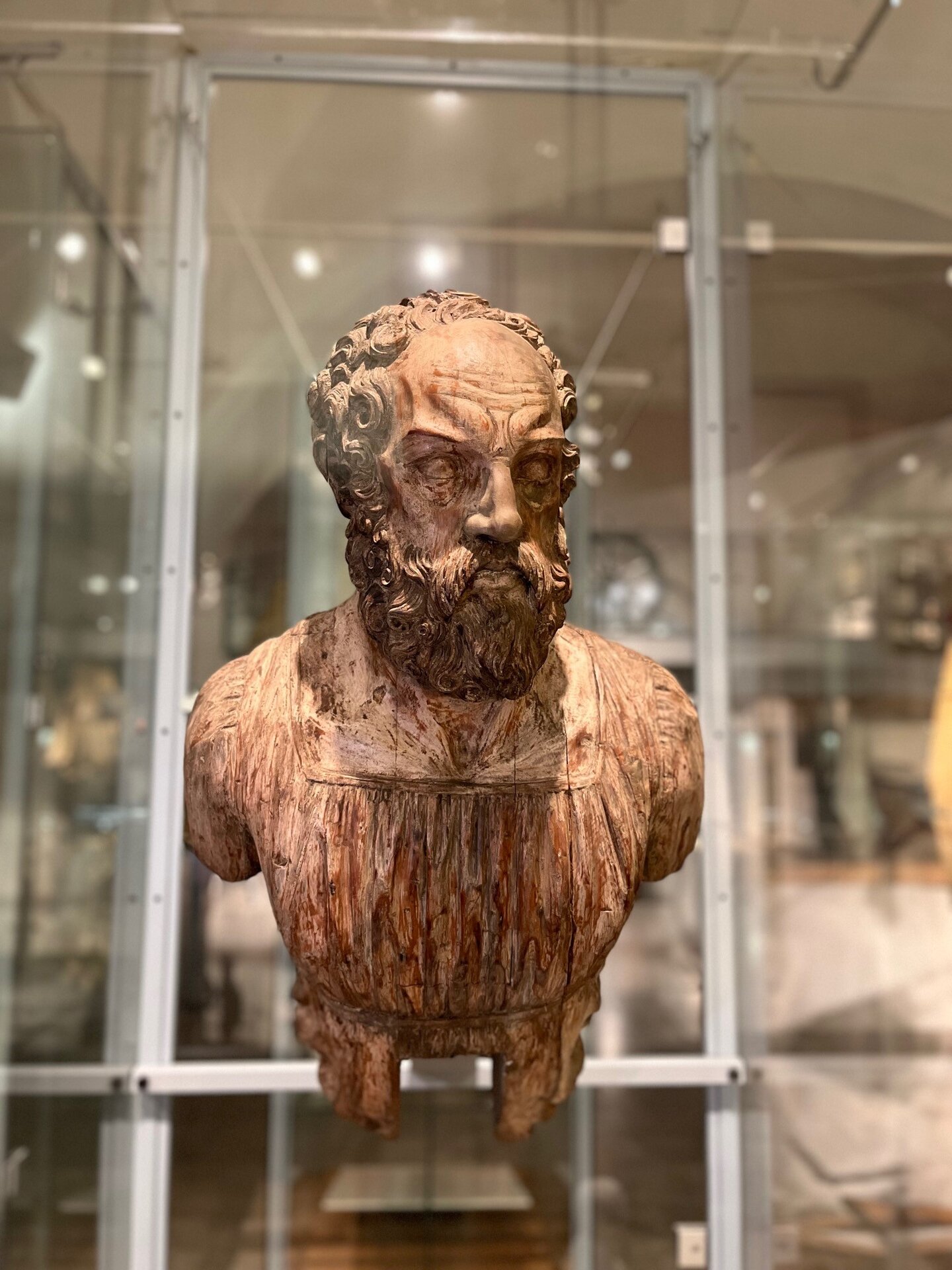 Zu sehen ist eine hölzerne Galionsfigur in Form einer bärtigen Männerbüste mit lockigem Haar und ernstem Gesichtsausdruck.