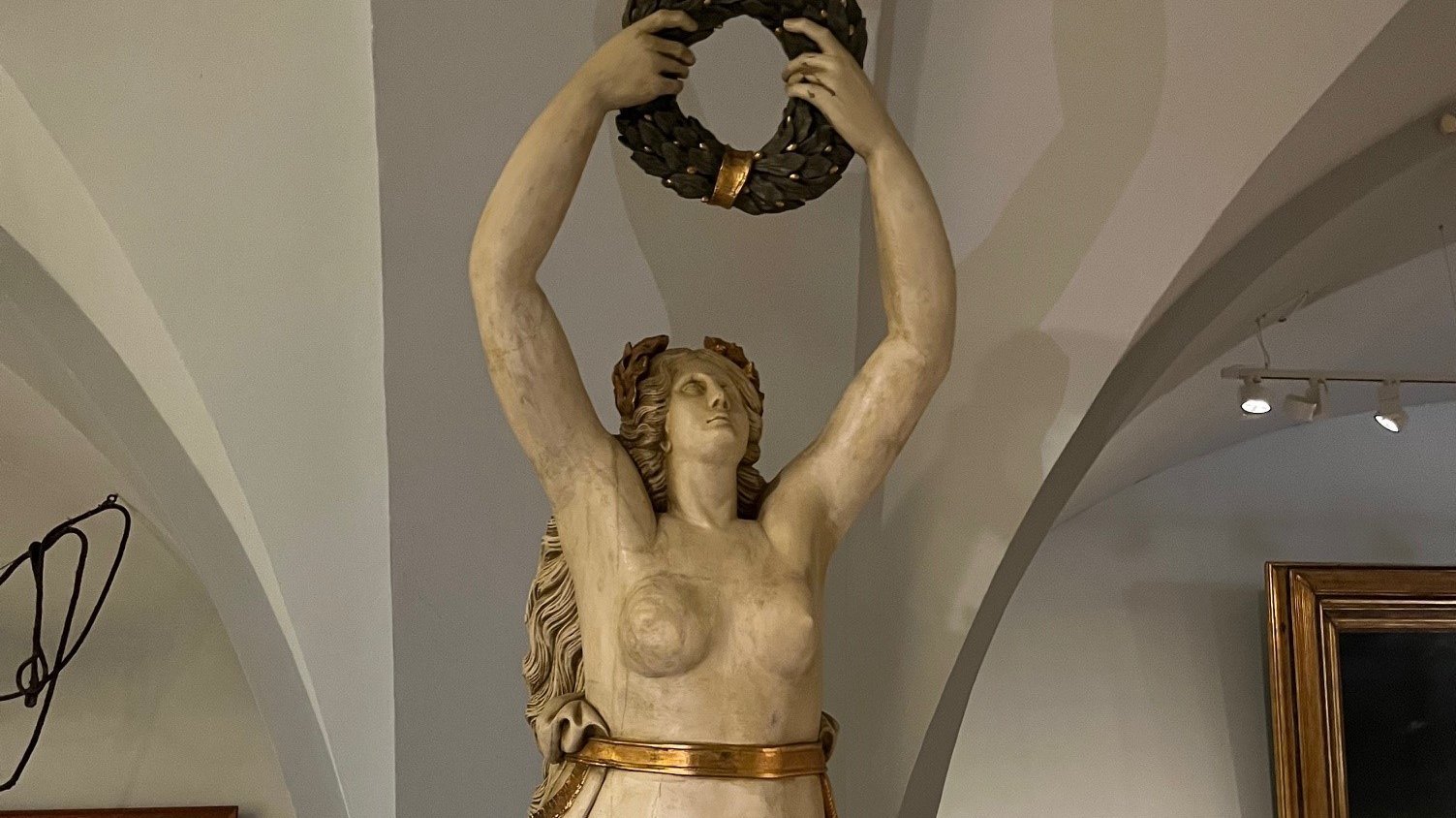 Das Bild zeigt die nackte Galionsfigur der Korvette Helgoland, dargestellt als weibliche „Meer Fee“ mit fließenden Haaren, die anmutig und elegant gestaltet ist und den Bug des Kriegsschiffs schmückte.   