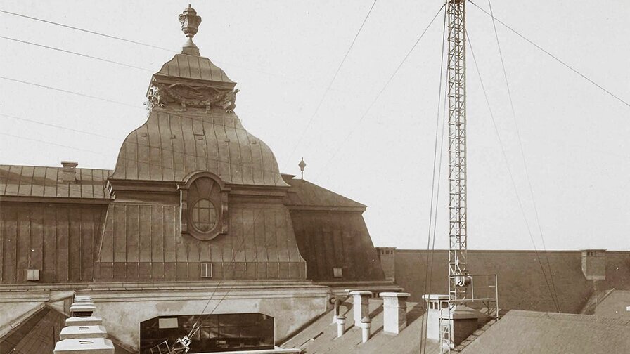 Das Bild zeigt eine schwarz-weiß Foto einer großen Radioantenne auf einem Dach. 